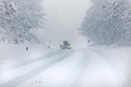 Plow on snow covered road in blizzard conditions